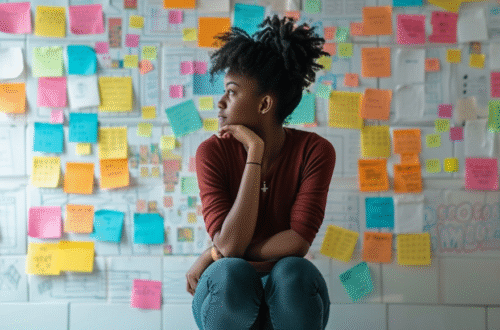 Woman looking sideways, with a board of full of colorful post-it notes behind her