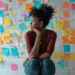 Woman looking sideways, with a board of full of colorful post-it notes behind her