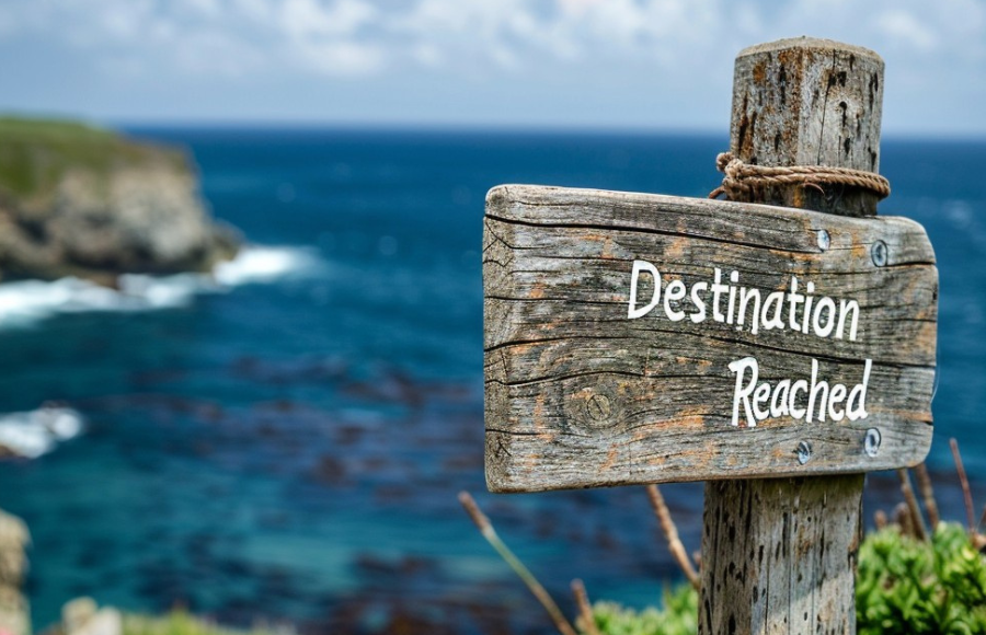 Beach alcove with rusty 'Destination Reached' wooden weathered sign.