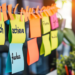A string of post it notes, like on a makeshift washing line but in an office.
