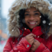 Beautiful black woman, in the falling snow, in red winter coat with fur hood