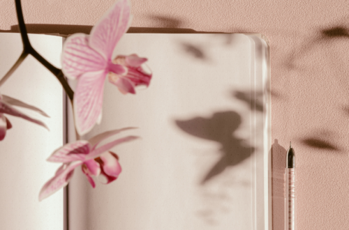 Open blank note book with a pen and butterfly flowers floating off the page