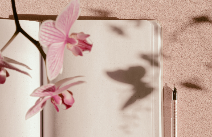 Open blank note book with a pen and butterfly flowers floating off the page