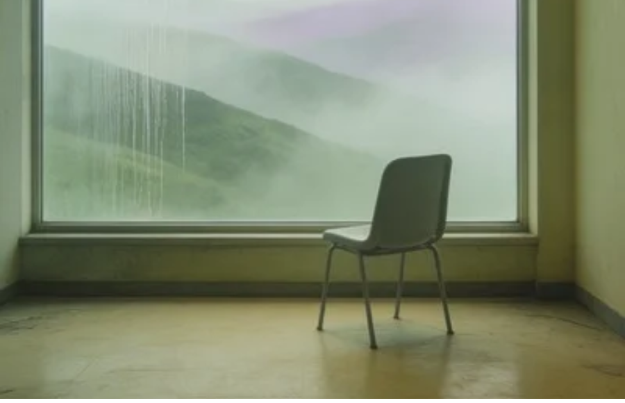 Lone chair facing a large window and misty weather