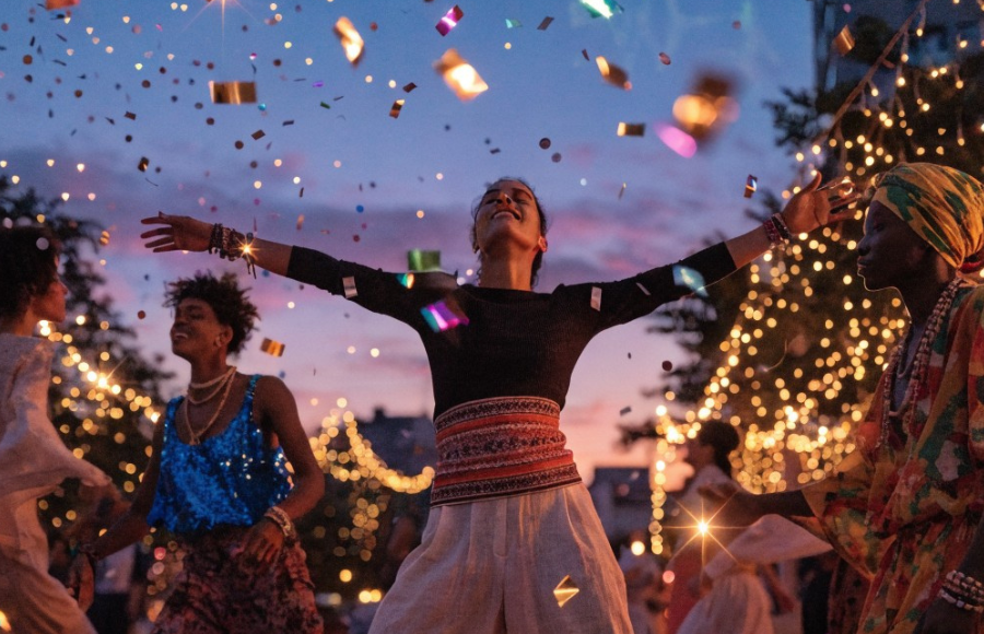 3 women in a fiesta celebration, center woman's arms wide open, happy, powerful