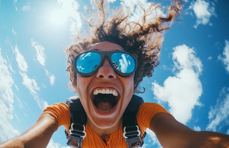 Fearless sky-diving woman, in living color, beautiful sky, she's filled with joy and excitement