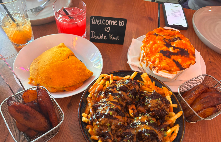 A restaurant table, colorful, full of delicious Caribbean food at the restaurant Double Knot, London UK.