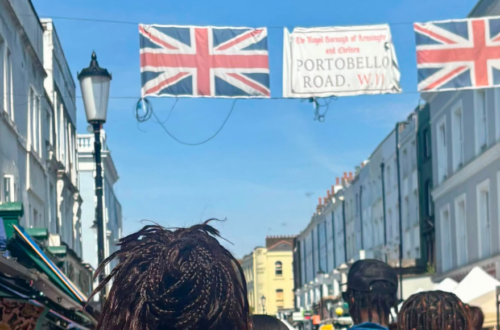 Photo - back of IreneB kids and fam walking under the Portobello Road banner with two Union Jack flags.