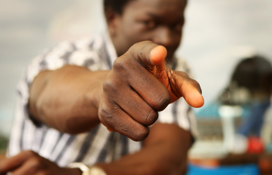 SincerelyIreneb, Vote, November midterms 2026, close up and blurred shot of a black man, his hand is in focus, pointing a finger to indicate pointing at a person - you - to take action.